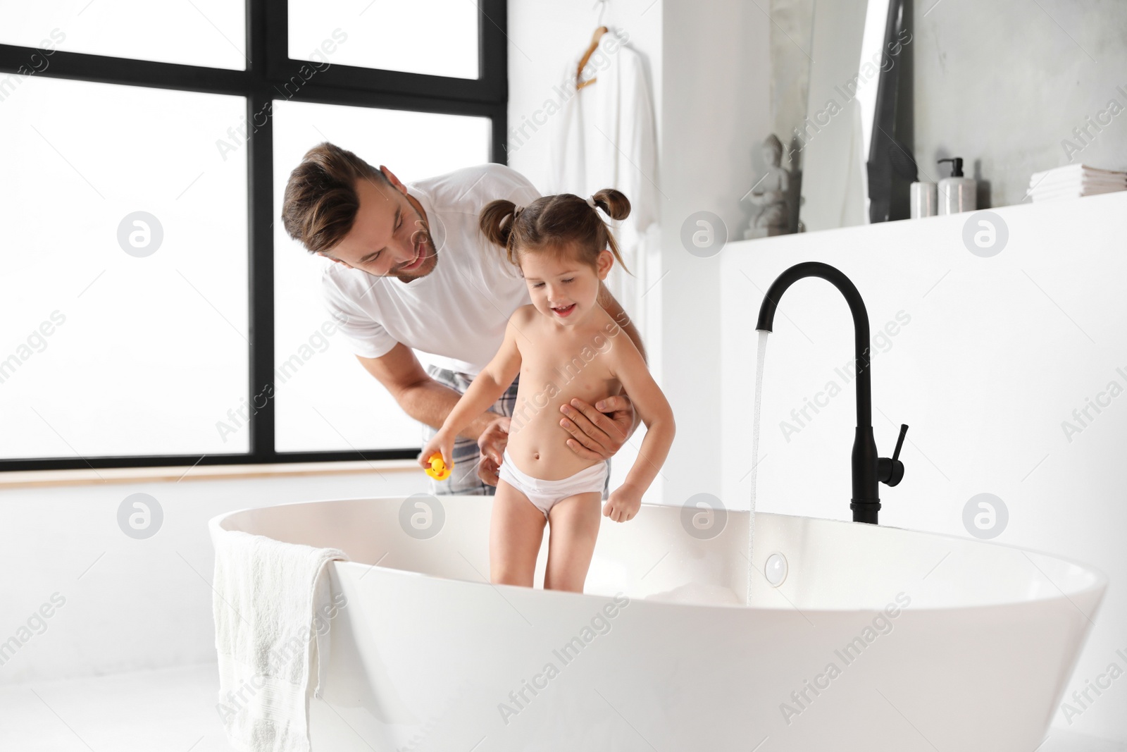 Young father with cute little daughter in bathroom Photo of Young father with cute little daughter in bathroom