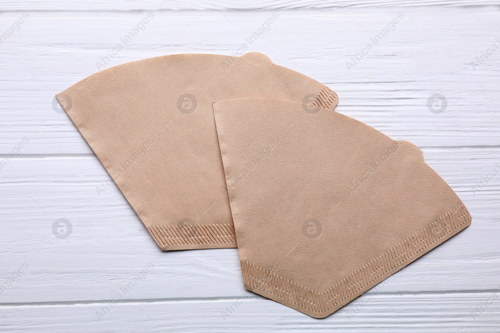 Photo of Paper coffee filters on white wooden table, flat lay