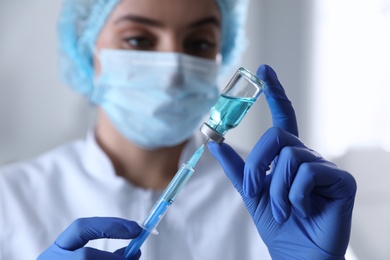 Doctor filling syringe with medication in clinic, focus on hands. Vaccination and immunization Photo of Doctor filling syringe with medication in clinic, focus on hands. Vaccination and immunization