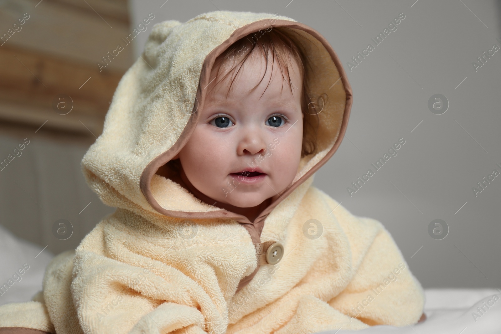 Cute little baby in yellow hooded towel on bed after bath Photo of Cute little baby in yellow hooded towel on bed after bath