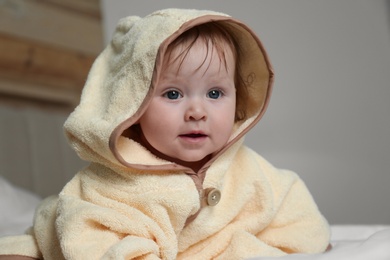 Cute little baby in yellow hooded towel on bed after bath Photo of Cute little baby in yellow hooded towel on bed after bath