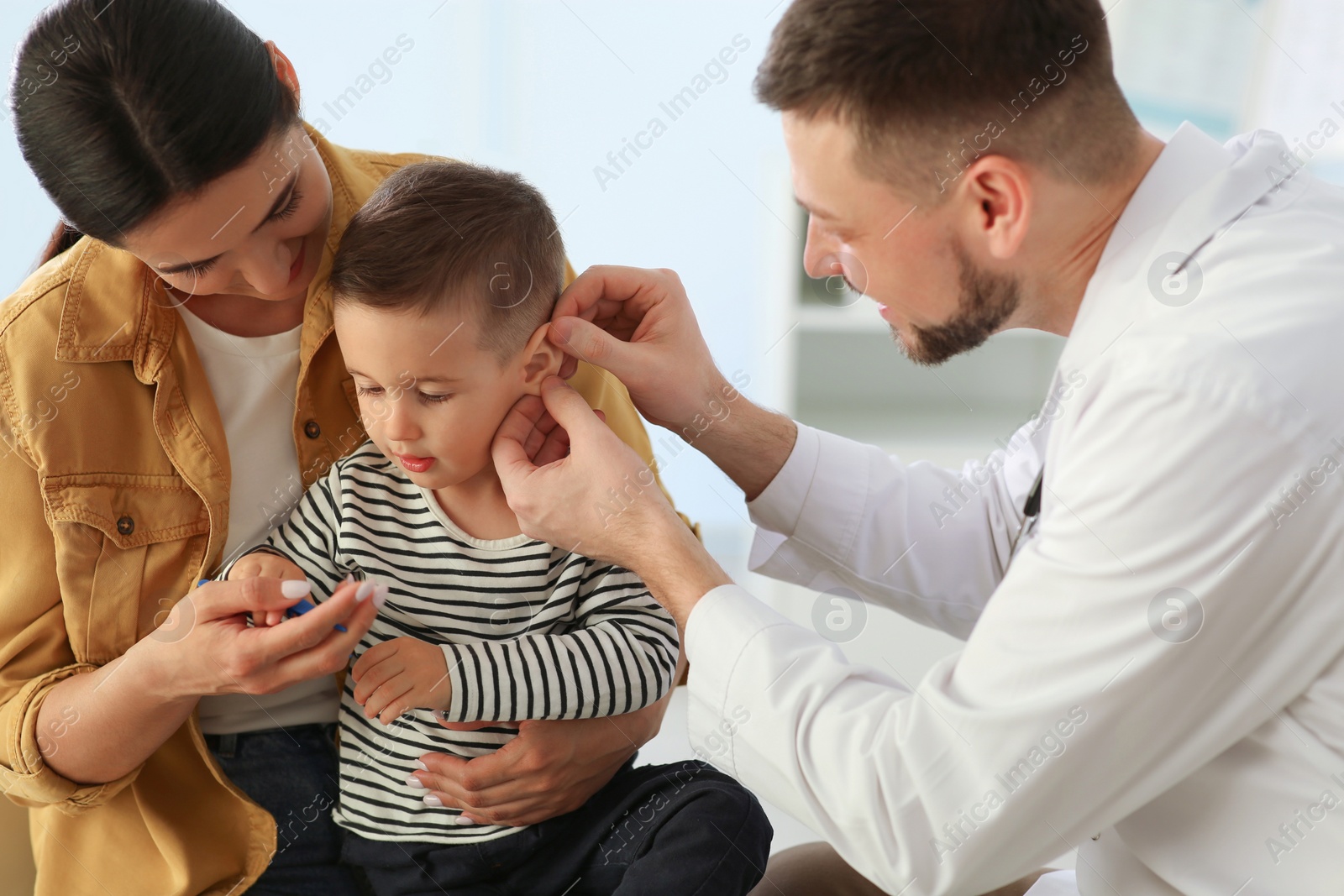 Mother and son visiting pediatrician in hospital. Doctor examining little boy Photo of Mother and son visiting pediatrician in hospital. Doctor examining little boy