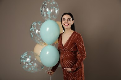 Happy pregnant woman with balloons near dark wall. Baby shower party Photo of Happy pregnant woman with balloons near dark wall. Baby shower party