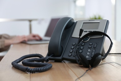 Desktop telephone with headset on wooden table in office. Hotline service Photo of Desktop telephone with headset on wooden table in office. Hotline service