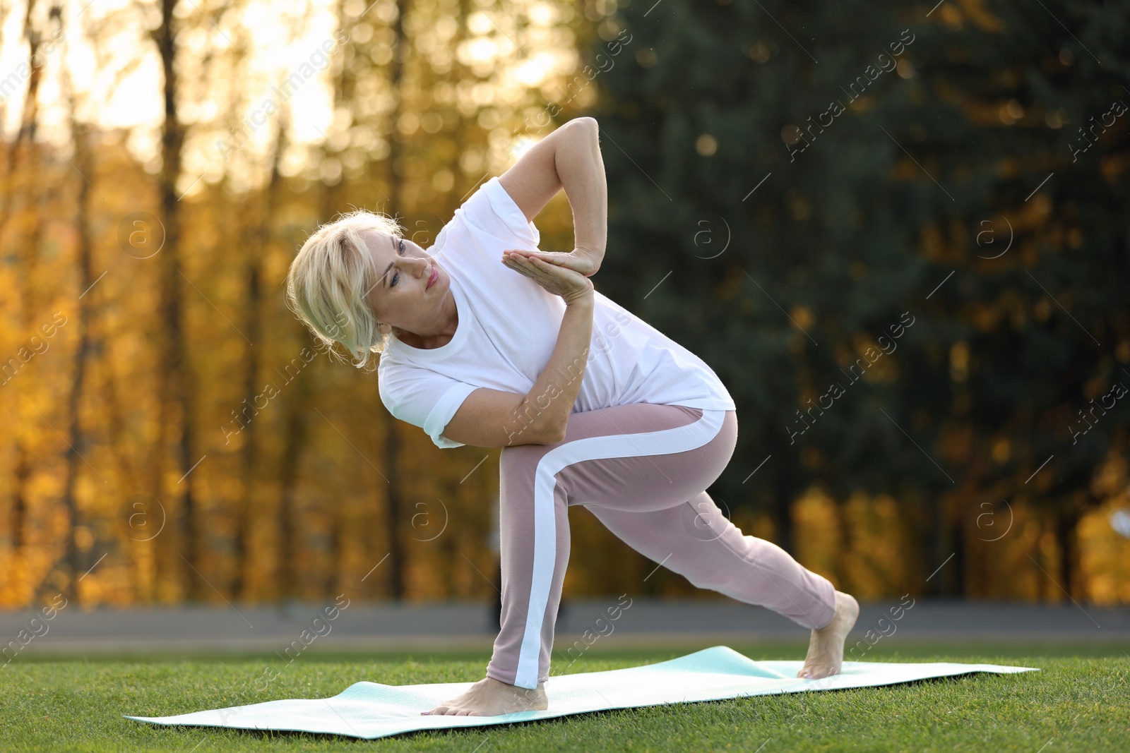 Mature woman practicing yoga on green grass in park Image of Mature woman practicing yoga on green grass in park