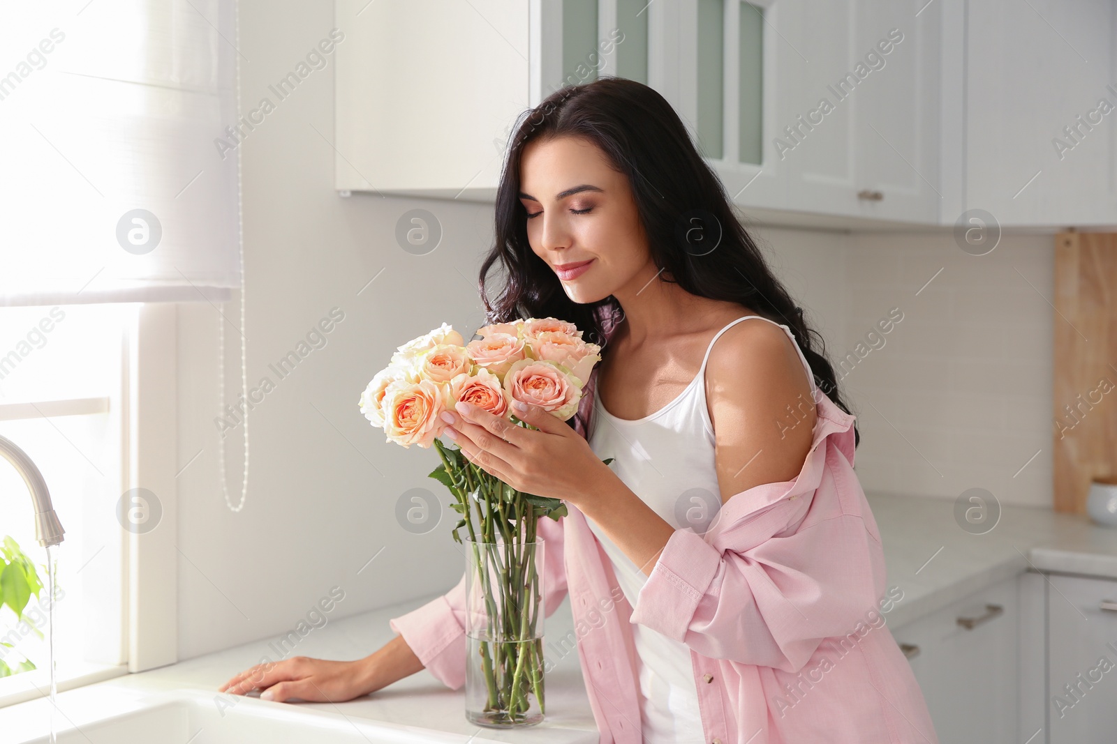 Young woman with beautiful bouquet in kitchen Photo of Young woman with beautiful bouquet in kitchen