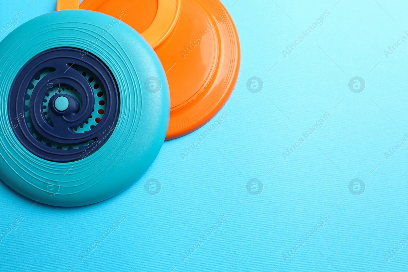 Plastic frisbee disks and ring on light blue background, flat lay. Space for text Photo of Plastic frisbee disks and ring on light blue background, flat lay. Space for text