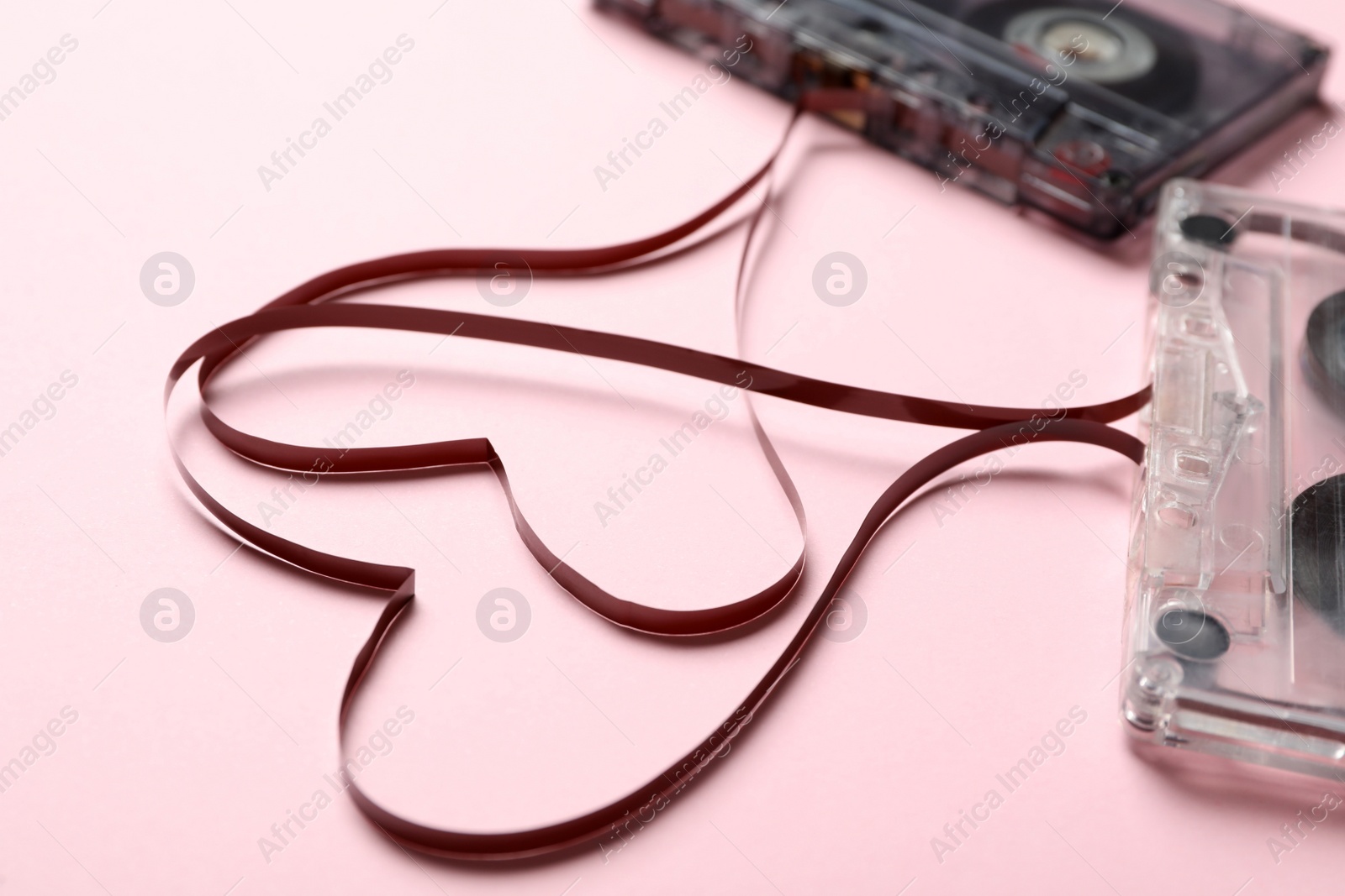 Music cassettes and hearts made of tape on pink background, closeup. Listening love songs Photo of Music cassettes and hearts made of tape on pink background, closeup. Listening love songs
