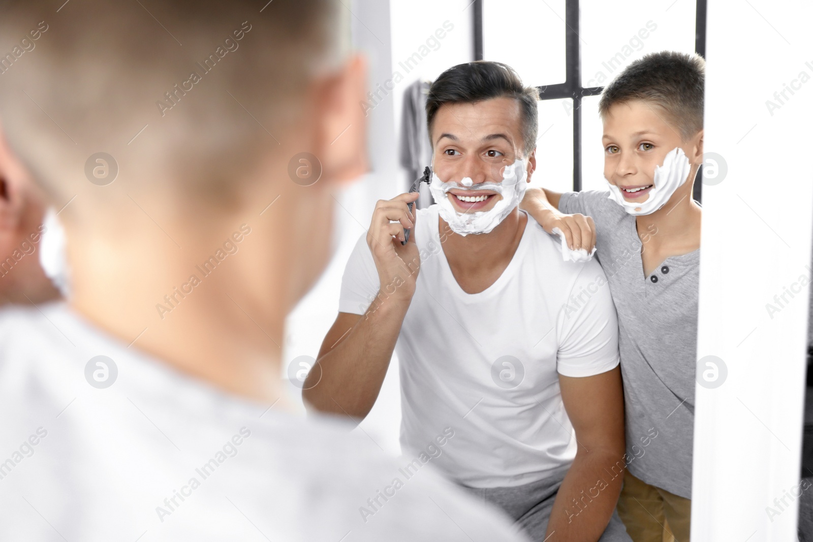 Dad showing his son how to shave near mirror in bathroom Photo of Dad showing his son how to shave near mirror in bathroom