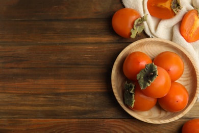 Tasty ripe persimmons on wooden table, flat lay. Space for text Photo of Tasty ripe persimmons on wooden table, flat lay. Space for text