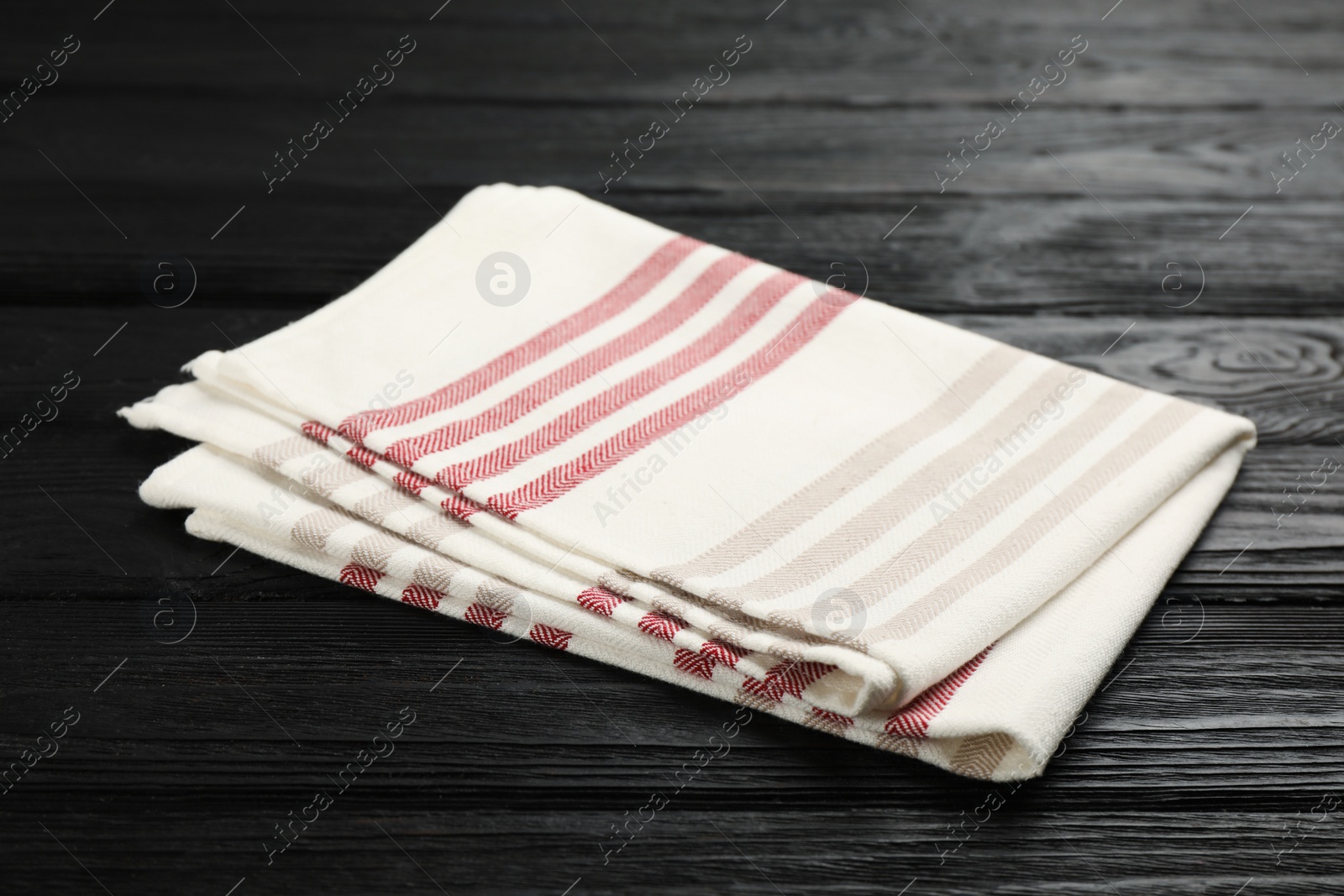 Striped kitchen towel on black wooden table Photo of Striped kitchen towel on black wooden table