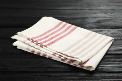 Striped kitchen towel on black wooden table Photo of Striped kitchen towel on black wooden table
