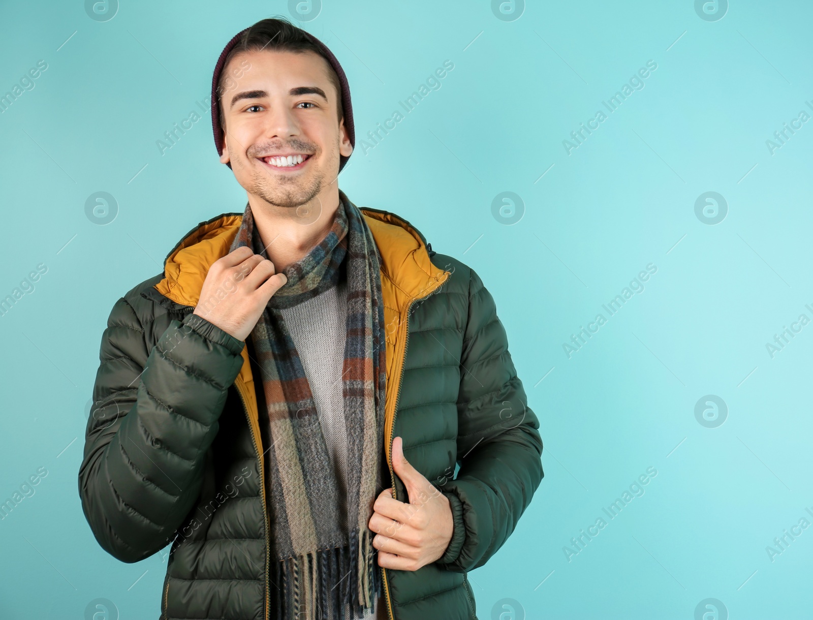 Portrait of happy young man in warm clothing on color background. Ready for winter vacation Photo of Portrait of happy young man in warm clothing on color background. Ready for winter vacation