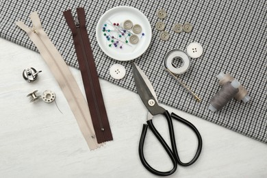 Flat lay composition with different sewing supplies and fabric on white wooden table Photo of Flat lay composition with different sewing supplies and fabric on white wooden table