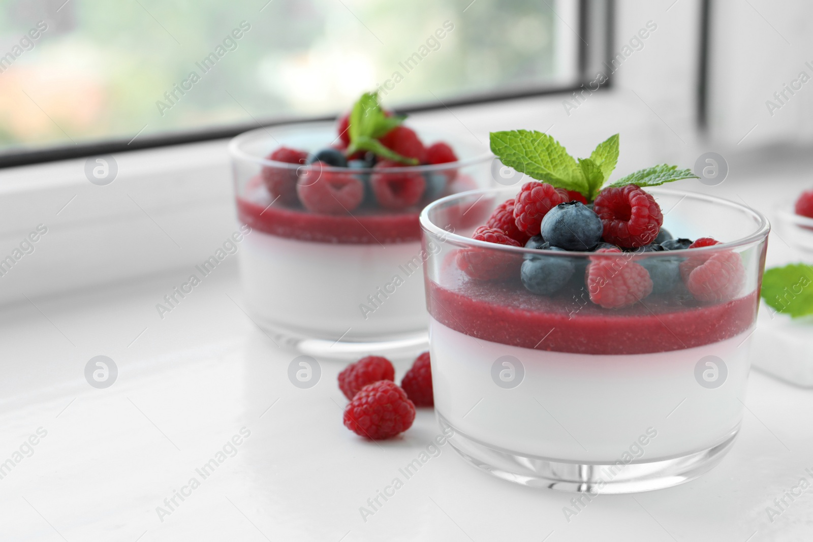 Delicious panna cotta with berries on window sill Photo of Delicious panna cotta with berries on window sill