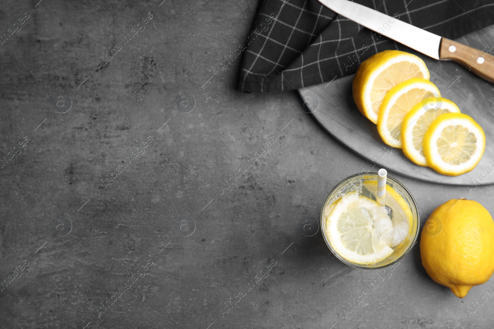 Soda water with lemon slices and ice cubes on grey table, flat lay. Space for text Photo of Soda water with lemon slices and ice cubes on grey table, flat lay. Space for text