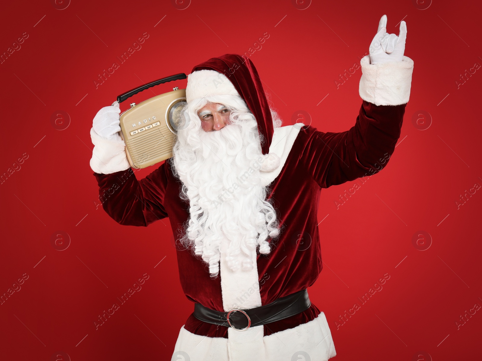 Photo of Santa Claus with vintage radio on red background. Christmas music