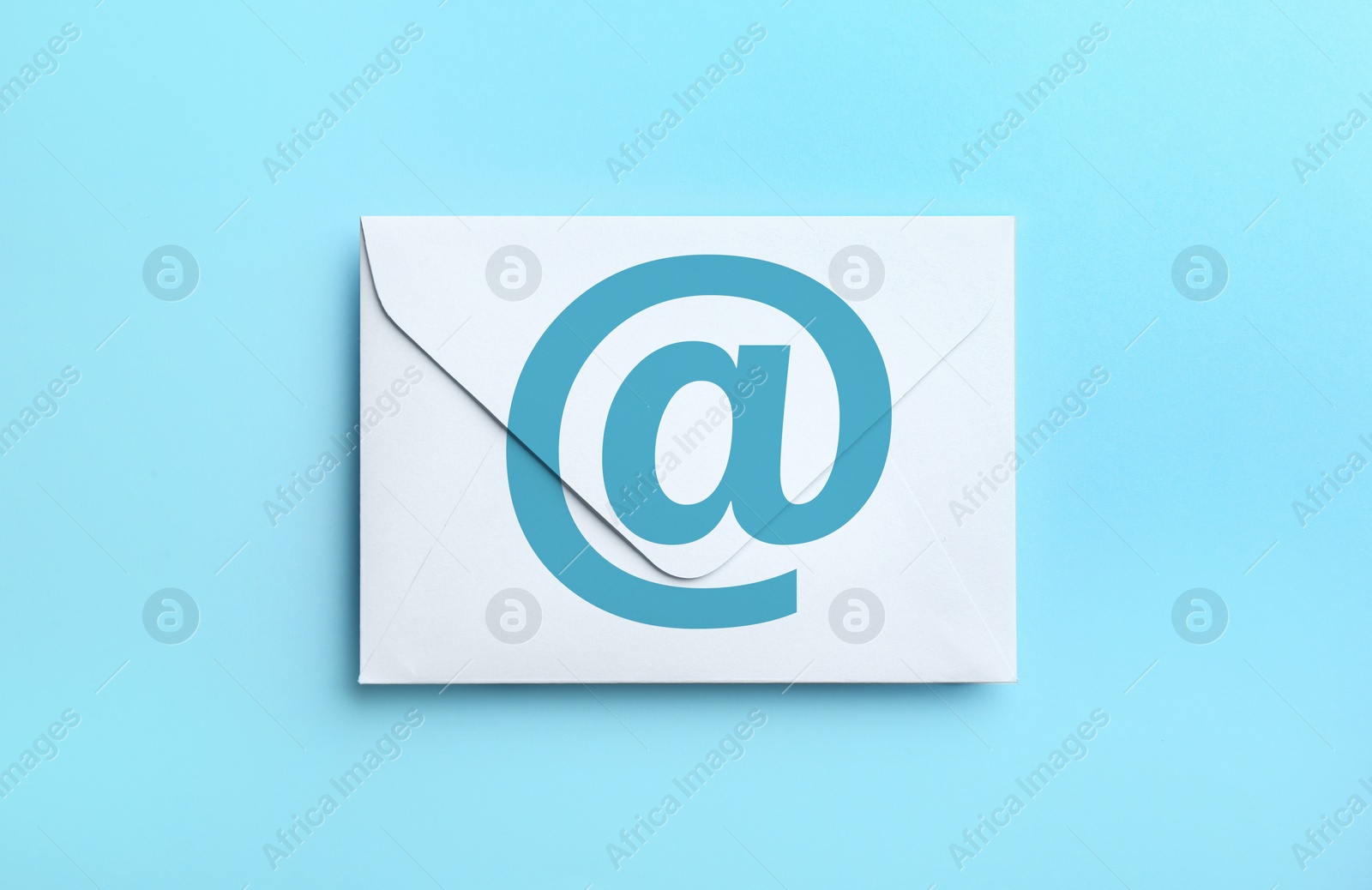 White paper envelope with at sign on light blue background, top view. Email service Image of White paper envelope with at sign on light blue background, top view. Email service
