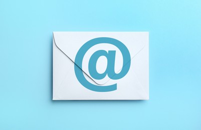 White paper envelope with at sign on light blue background, top view. Email service Image of White paper envelope with at sign on light blue background, top view. Email service