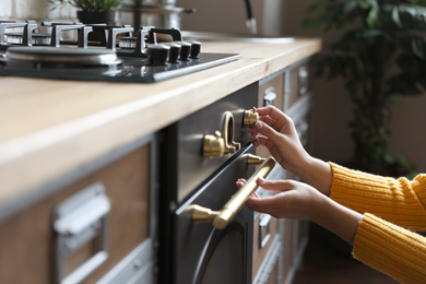 Woman using modern oven in kitchen, closeup Photo of Woman using modern oven in kitchen, closeup