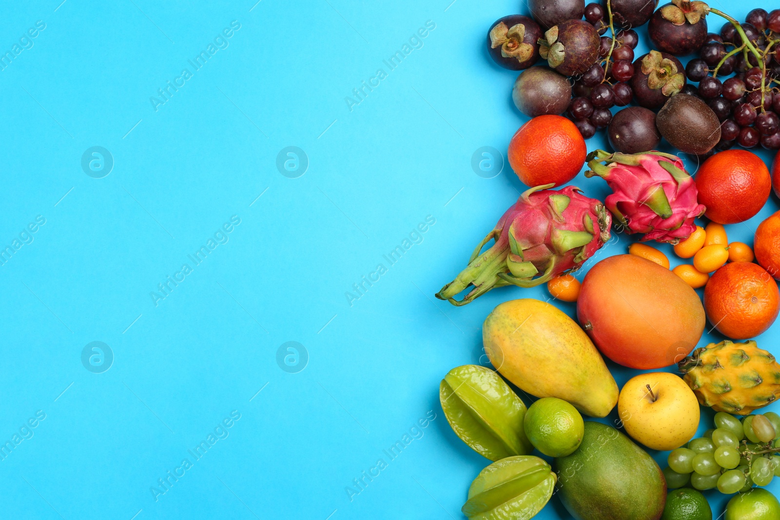 Assortment of fresh exotic fruits on light blue background, flat lay. Space for text Photo of Assortment of fresh exotic fruits on light blue background, flat lay. Space for text