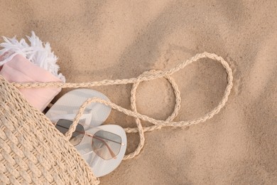 Beach bag with flip flops, towel and sunglasses on sand, top view. Space for text Photo of Beach bag with flip flops, towel and sunglasses on sand, top view. Space for text