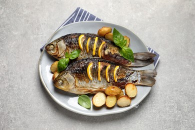 Tasty homemade roasted crucian carps with garnish on light grey table, top view. River fish Photo of Tasty homemade roasted crucian carps with garnish on light grey table, top view. River fish