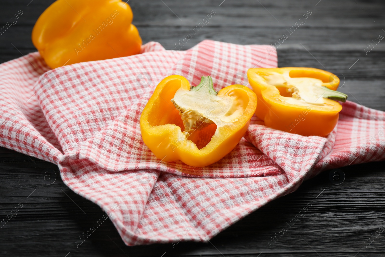 Kitchen towel and bell peppers on black wooden table Photo of Kitchen towel and bell peppers on black wooden table