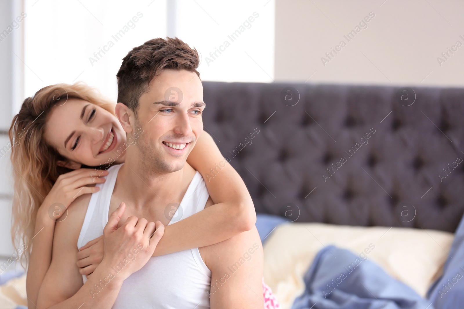 Photo of Happy young couple hugging on bed at home