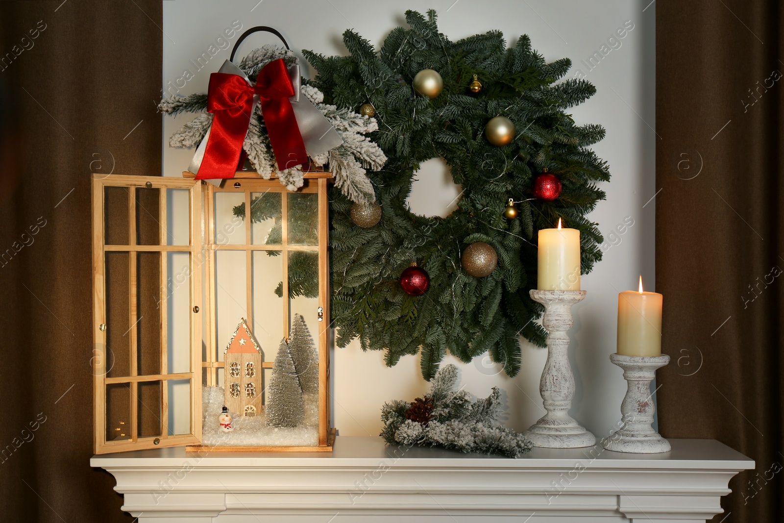 Beautiful festive lantern and candles on mantel near Christmas wreath Photo of Beautiful festive lantern and candles on mantel near Christmas wreath