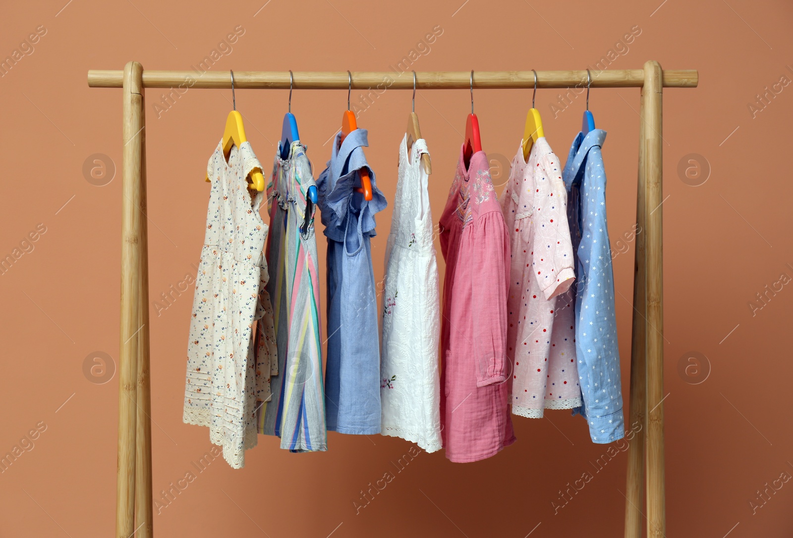 Rack with stylish children clothes on beige background Photo of Rack with stylish children clothes on beige background