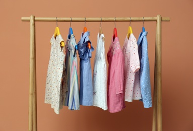 Rack with stylish children clothes on beige background Photo of Rack with stylish children clothes on beige background