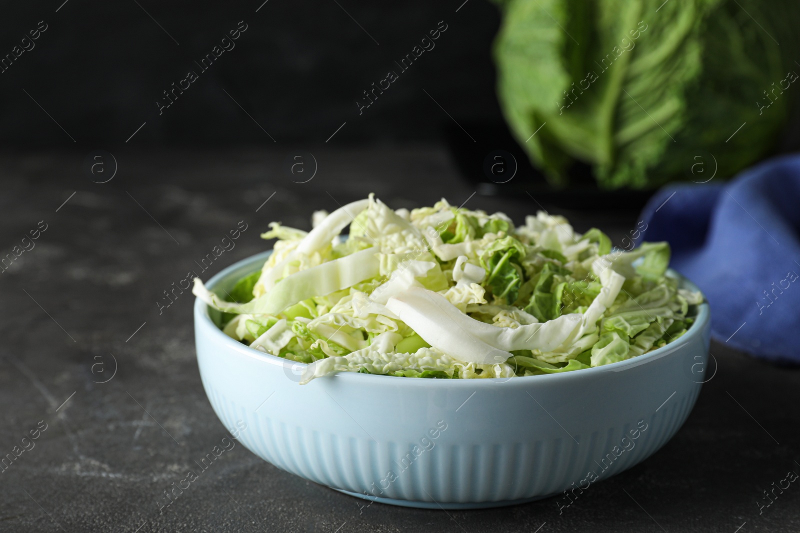 Cut fresh savoy cabbage in bowl on grey table, closeup Photo of Cut fresh savoy cabbage in bowl on grey table, closeup
