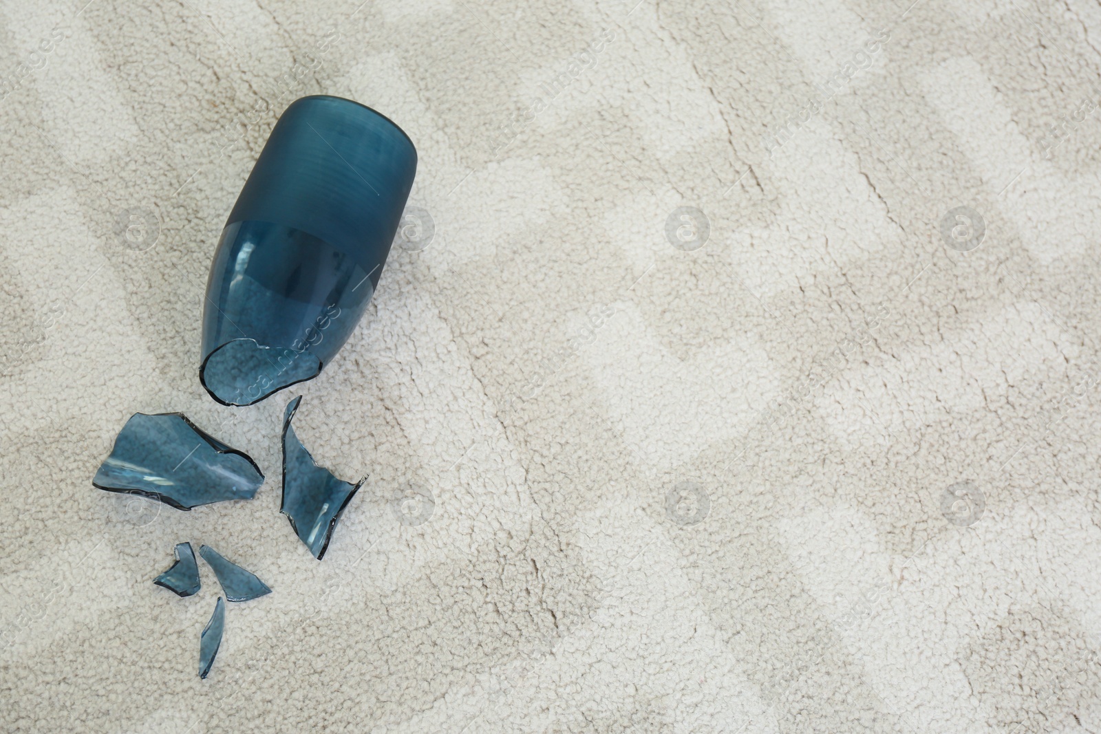 Broken blue glass vase on carpet, above view. Space for text Photo of Broken blue glass vase on carpet, above view. Space for text