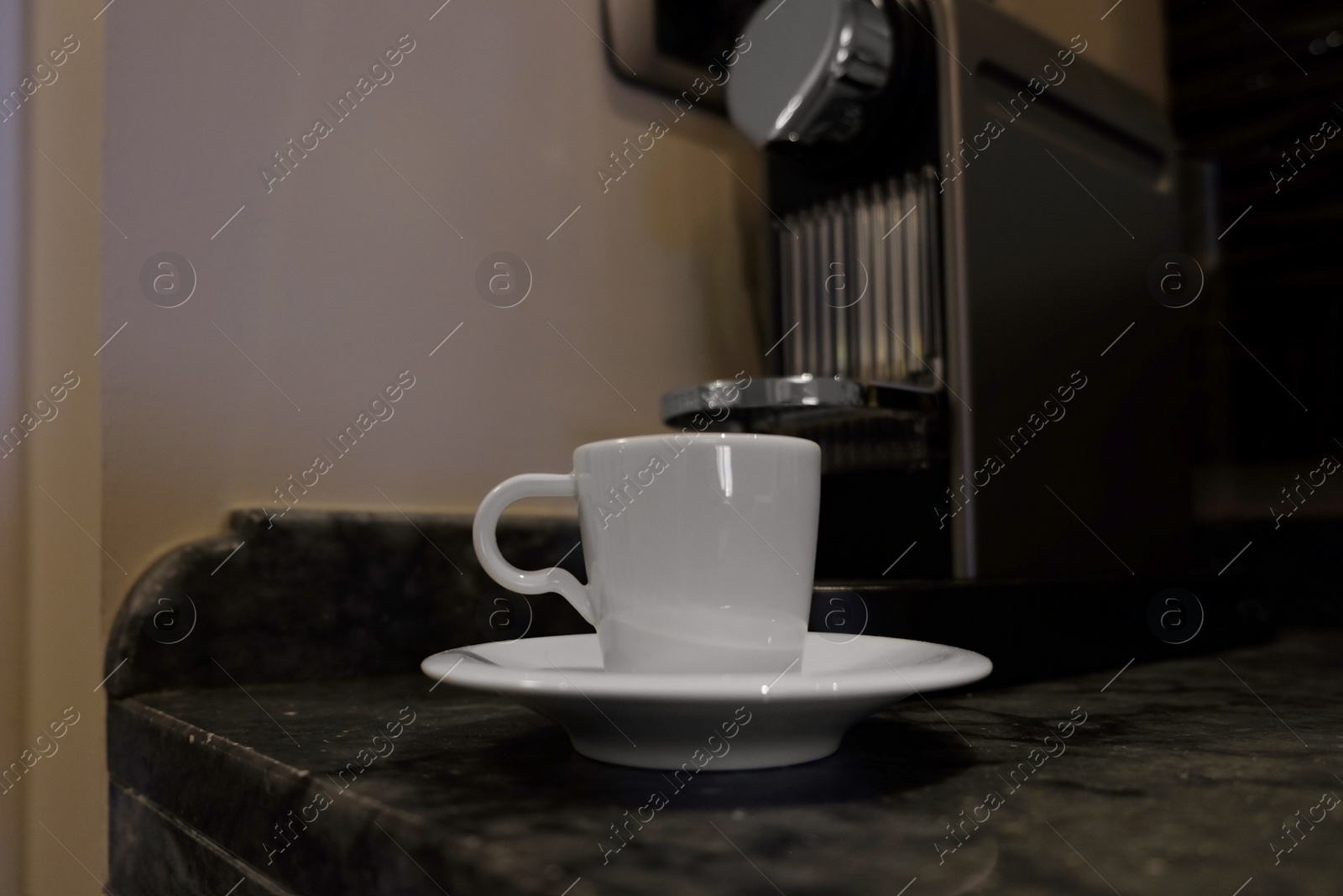 White cup near coffee machine on table Photo of White cup near coffee machine on table