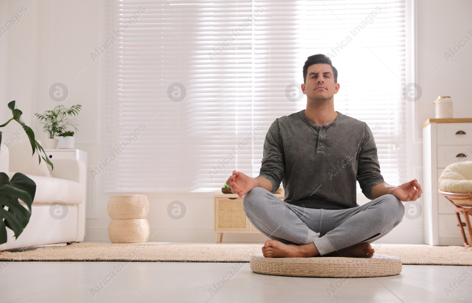 Man meditating on wicker mat at home. Space for text Photo of Man meditating on wicker mat at home. Space for text