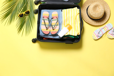 Photo of Flat lay composition with open suitcase on yellow background