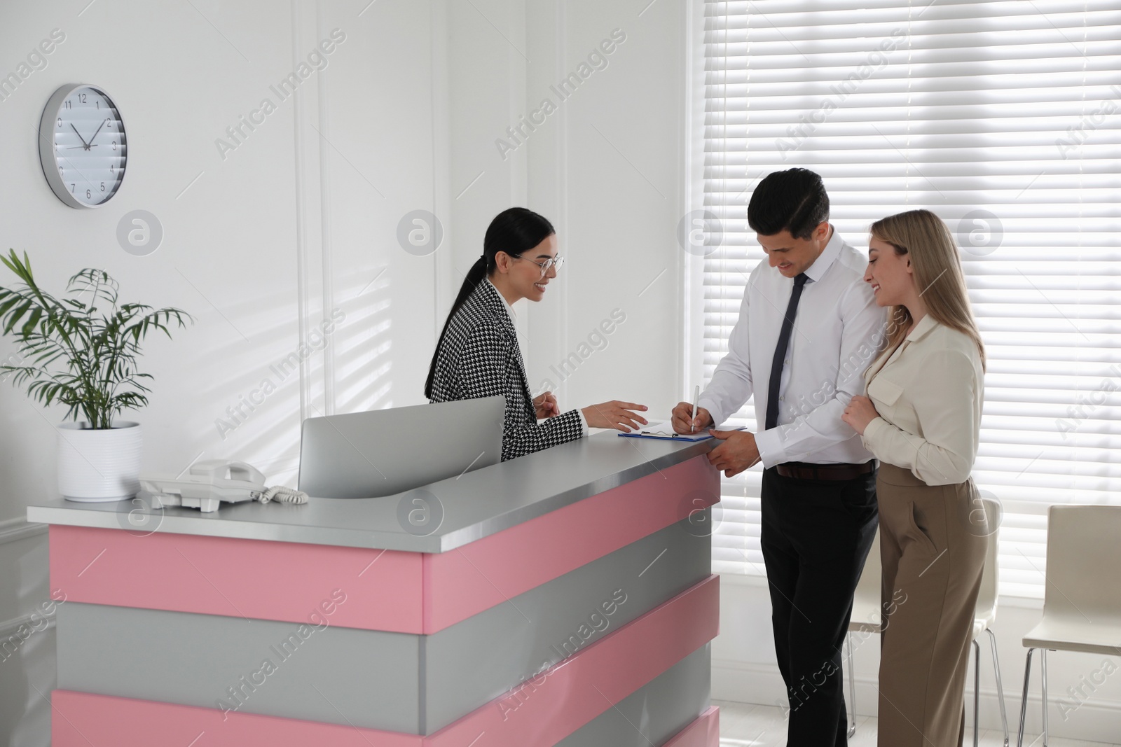 Receptionist working with clients at countertop in office Photo of Receptionist working with clients at countertop in office
