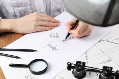Jeweler drawing sketch of elegant ring on paper at wooden table, closeup Photo of Jeweler drawing sketch of elegant ring on paper at wooden table, closeup
