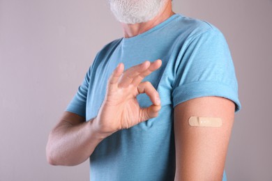 Senior man showing arm with bandage after vaccination on beige background, closeup Photo of Senior man showing arm with bandage after vaccination on beige background, closeup