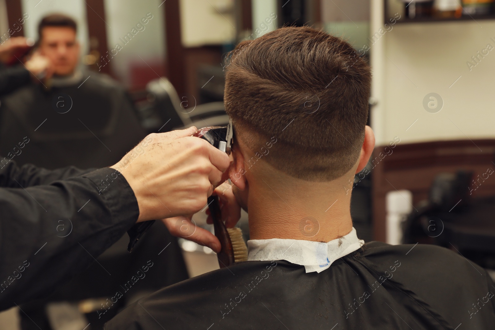 Professional hairdresser making stylish haircut in salon, back view Photo of Professional hairdresser making stylish haircut in salon, back view
