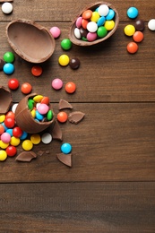 Broken chocolate eggs and colorful candies on wooden table, flat lay. Space for text Photo of Broken chocolate eggs and colorful candies on wooden table, flat lay. Space for text