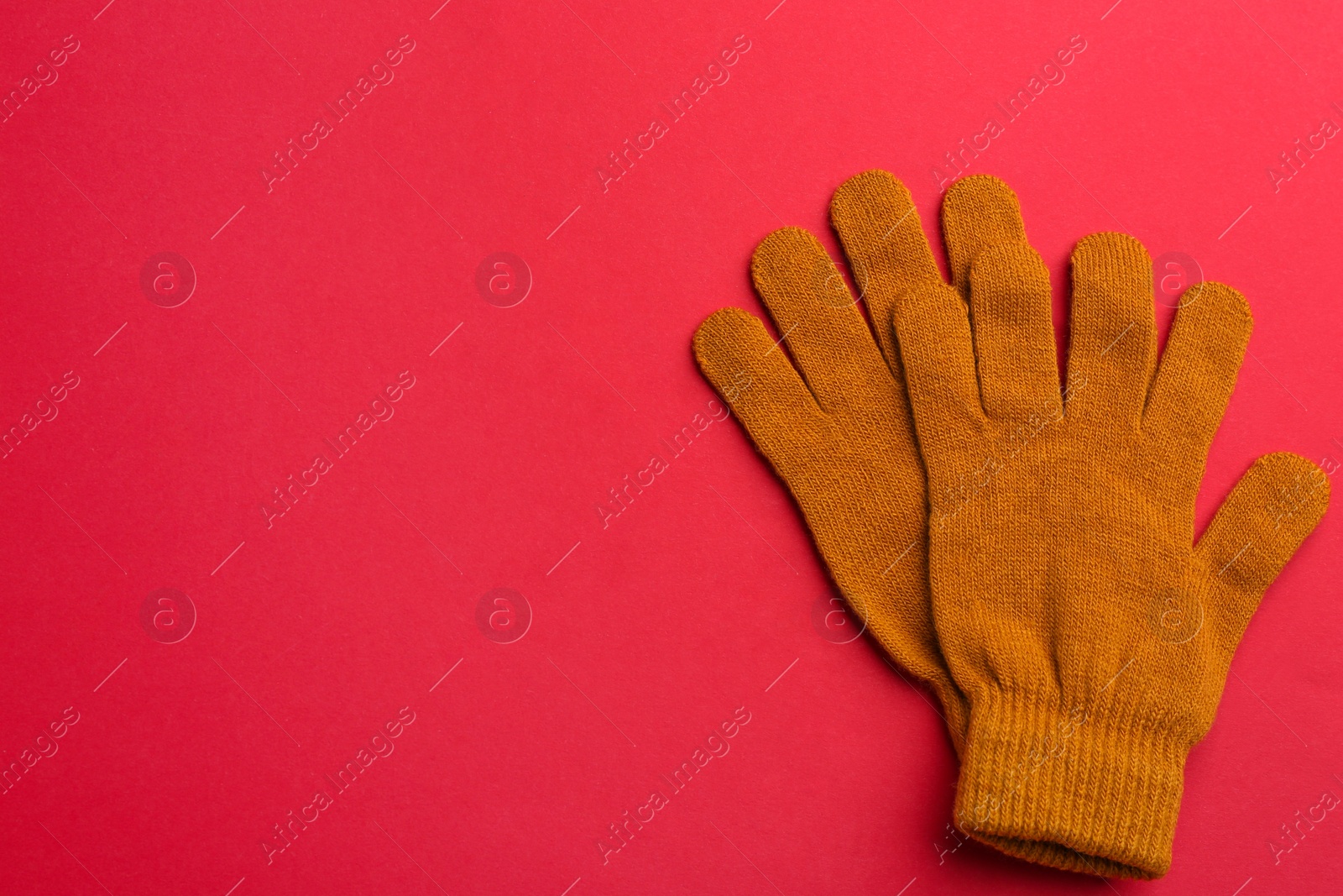 Pair of stylish woolen gloves on red background, flat lay. Space for text Photo of Pair of stylish woolen gloves on red background, flat lay. Space for text