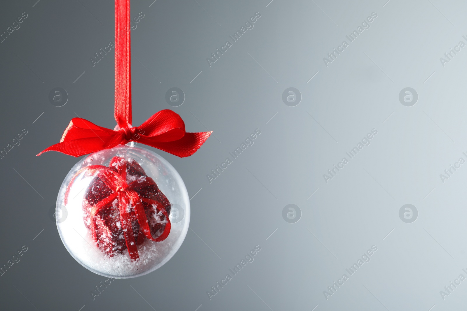 Decorative snow globe hanging on grey background, space for text Photo of Decorative snow globe hanging on grey background, space for text