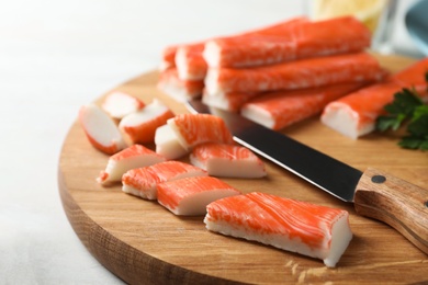 Sliced crab sticks and knife on wooden cutting board, closeup Photo of Sliced crab sticks and knife on wooden cutting board, closeup