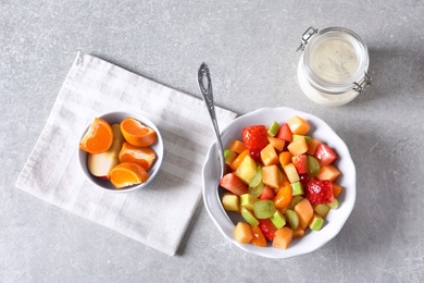 Bowl with fresh fruit salad on grey background Photo of Bowl with fresh fruit salad on grey background