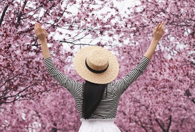 Young woman in park with blooming trees. Spring look Photo of Young woman in park with blooming trees. Spring look