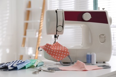 Sewing machine with cloth mask on table indoors Photo of Sewing machine with cloth mask on table indoors