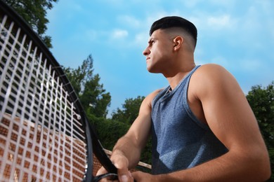 Man with tennis racket at court, low angle view Photo of Man with tennis racket at court, low angle view