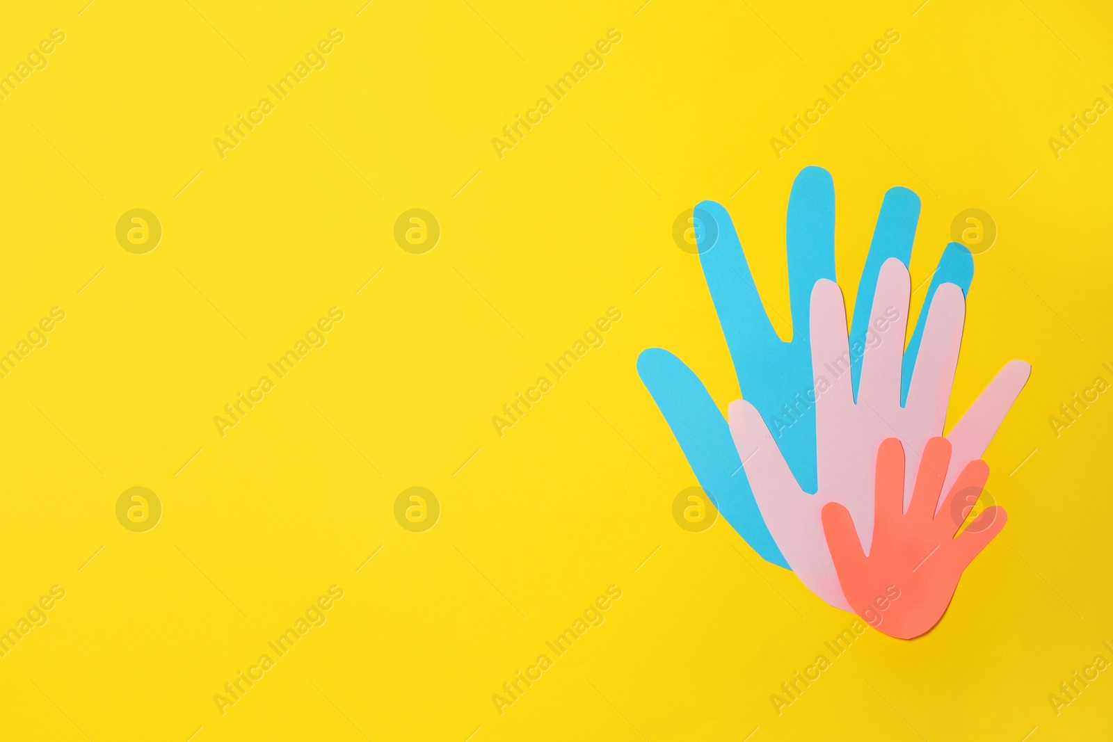 Paper palms symbolizing family on yellow background, top view. Space for text Photo of Paper palms symbolizing family on yellow background, top view. Space for text